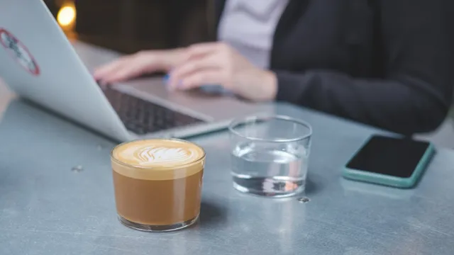 Freelancer typing on a laptop at a cafe table next to a cup of coffee