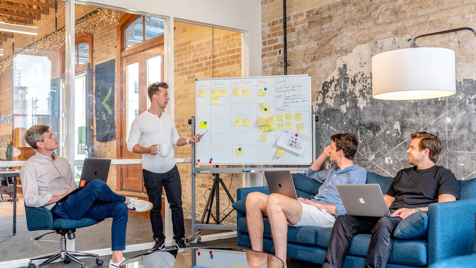 Presenter sketching a plan on a whiteboard while a small team watches